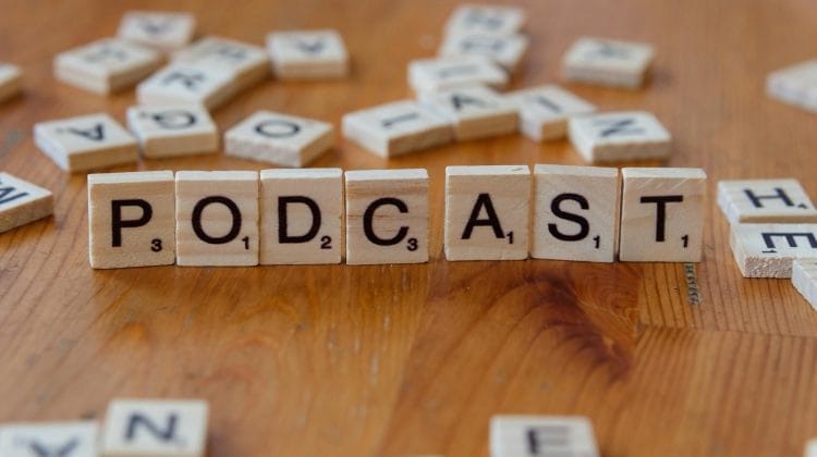 scrabble tiles spelling podcast on wooden table